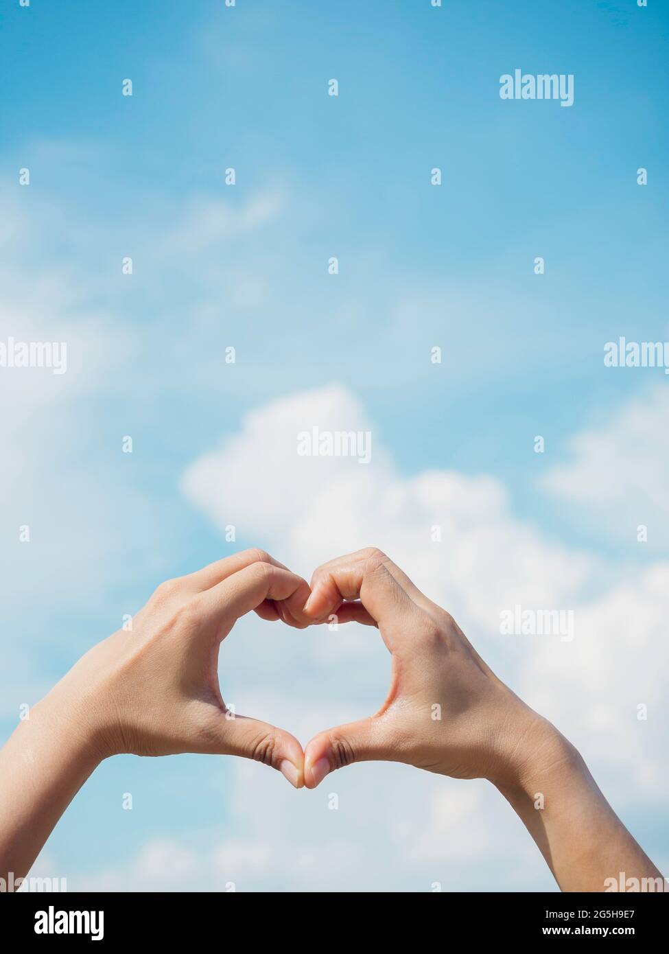 Heart shape hand on blue sky and fluffy cloud background, concept of ...