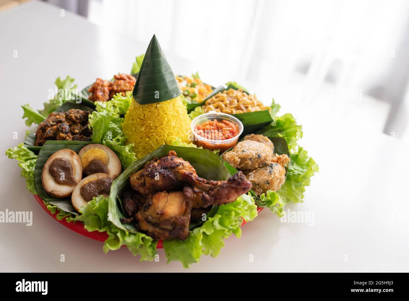 nasi tumpeng. indonesian cuisine yellow rice on banana leaf Stock Photo ...