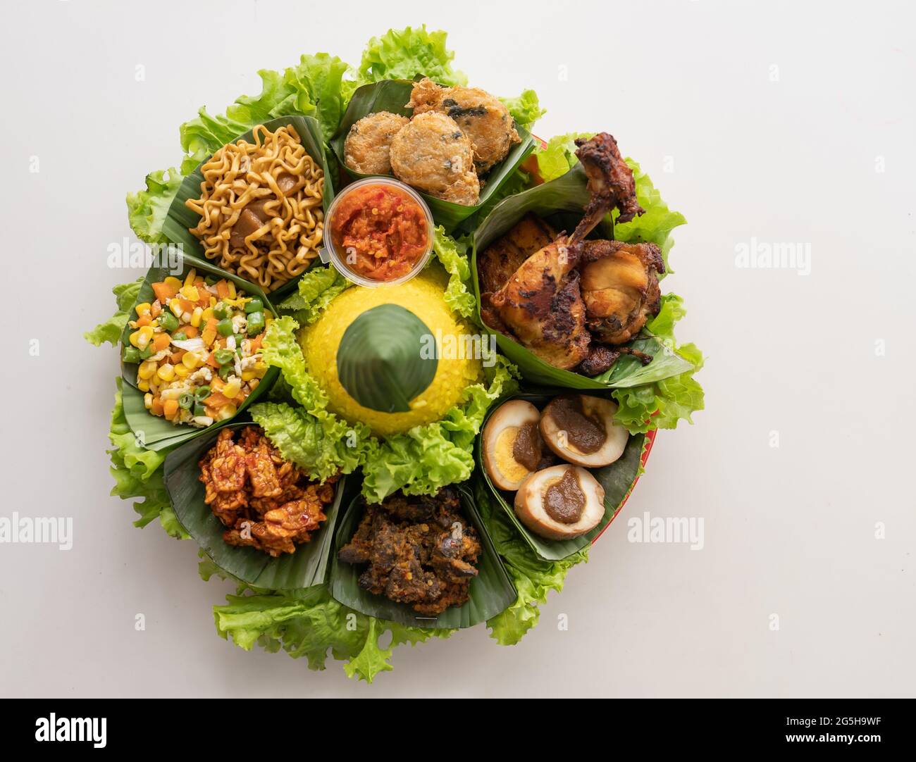 nasi tumpeng. indonesian cuisine yellow rice on banana leaf Stock Photo ...
