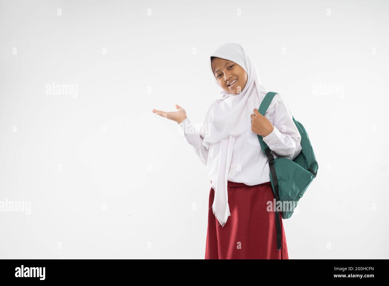 a chubby girl wearing a hooded elementary school uniform with gestures of  hands offering something while carrying a school bag Stock Photo - Alamy