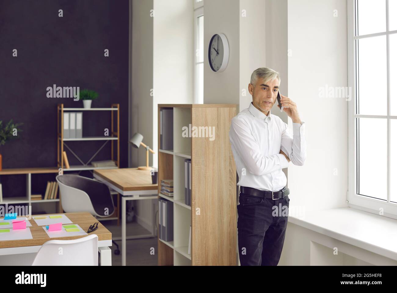 Senior businessman is busy talking on a mobile phone solving various problems at work. Stock Photo