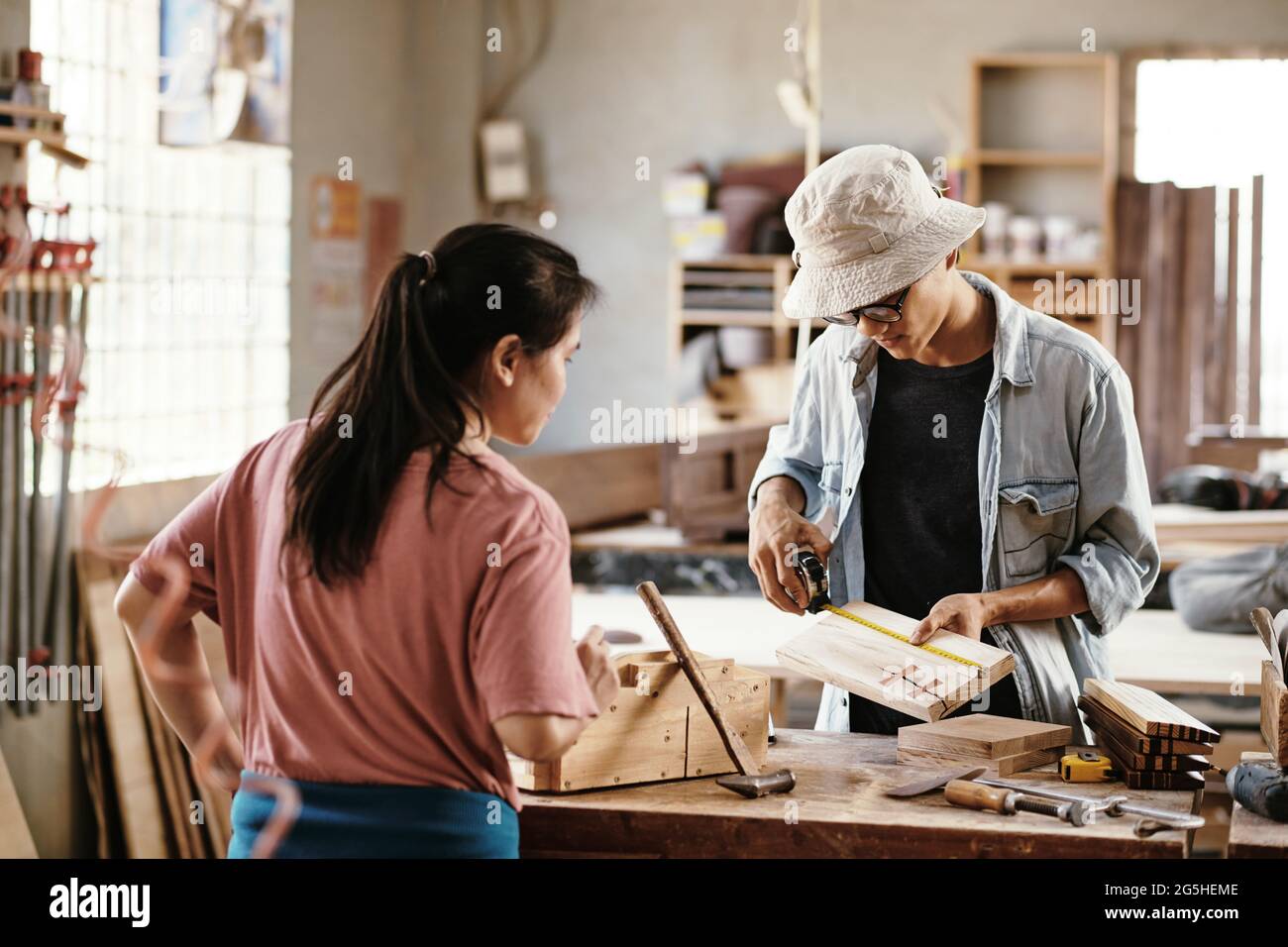 Young carpenters working on project, they are measurig wooden planks at