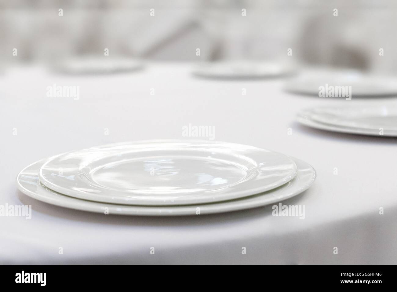 Empty white plates on a white tablecloth. Restaurant setting. Stock Photo