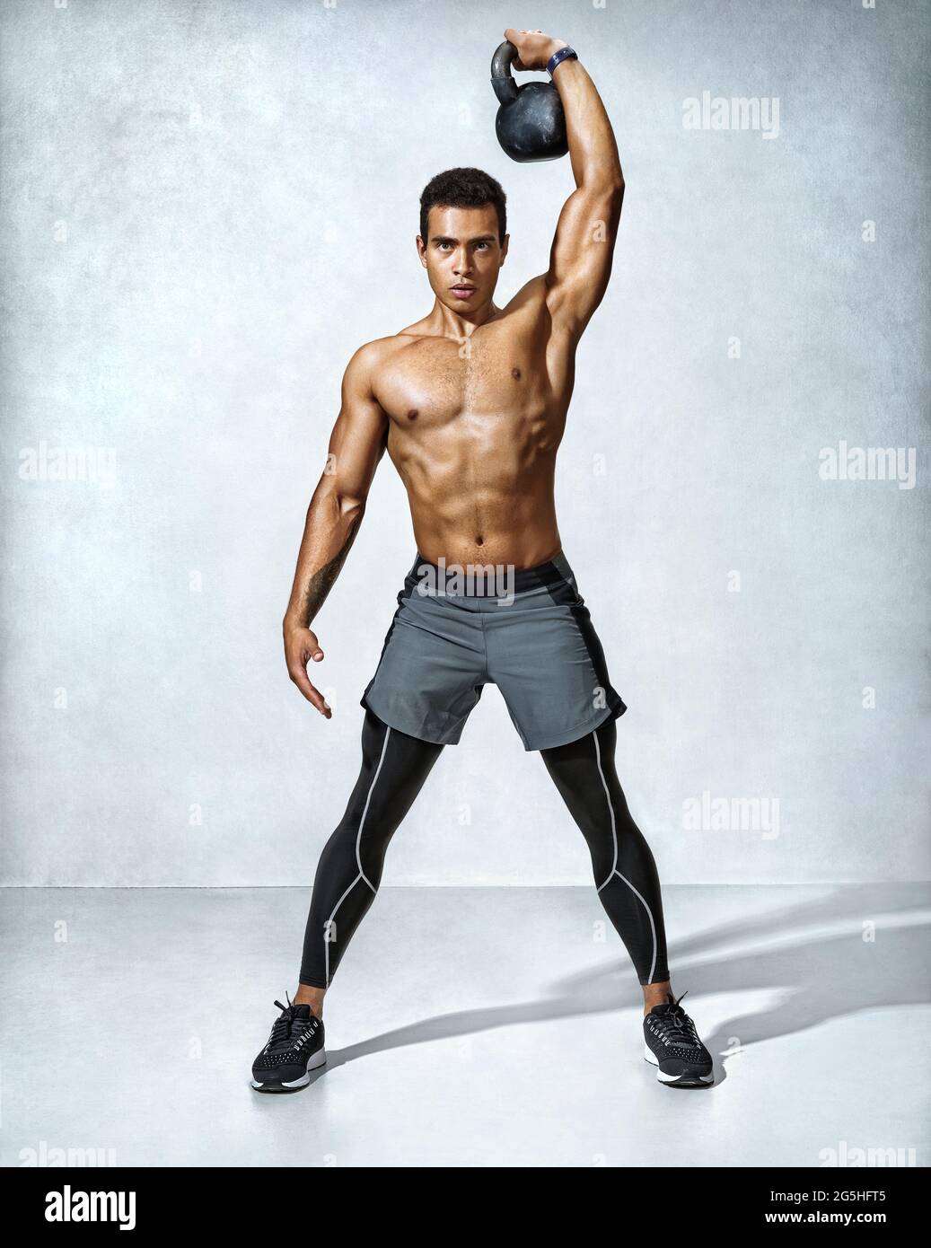 Young muscular guy training with kettlebell. Photo of handsome man with  naked torso on grey background. Strength and motivation. Full length Stock  Photo - Alamy