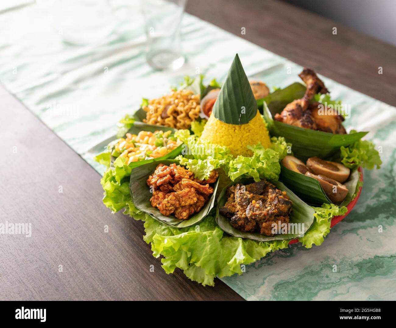 nasi tumpeng. indonesian cuisine yellow rice on banana leaf Stock Photo ...