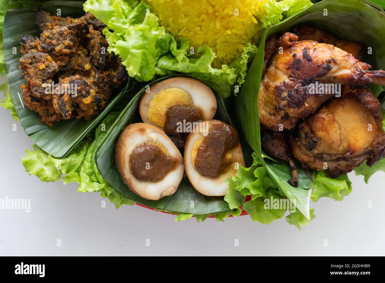 nasi tumpeng. indonesian cuisine yellow rice on banana leaf Stock Photo ...