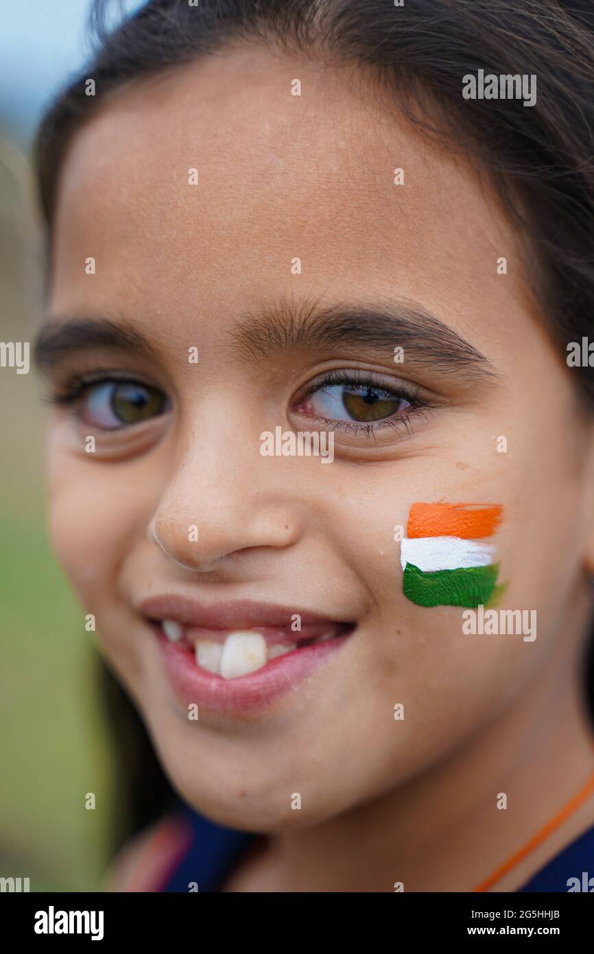 Closeup of Tricolor Indian flag Painted on happy smiling young girls Kid face during Indian Independence or republic day celebration - concept of Stock Photo