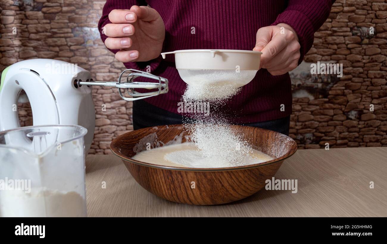 Sifting flour into a bowl. The cooking process. Selective focus. Stock Photo