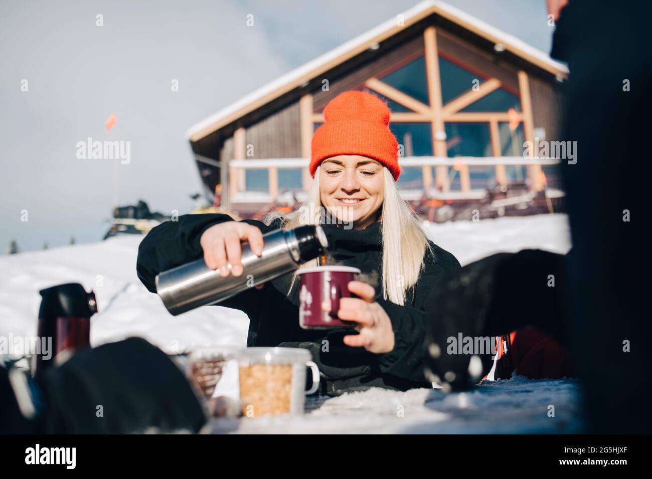 Smiling woman pouring coffee in cup during winter Stock Photo