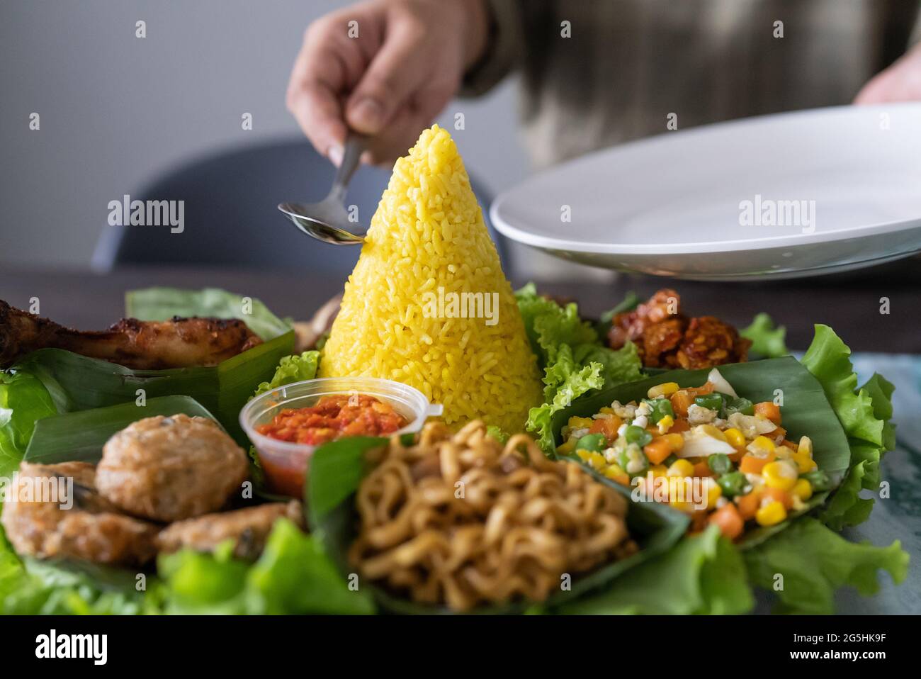 nasi tumpeng. indonesian cuisine yellow rice on banana leaf Stock Photo ...
