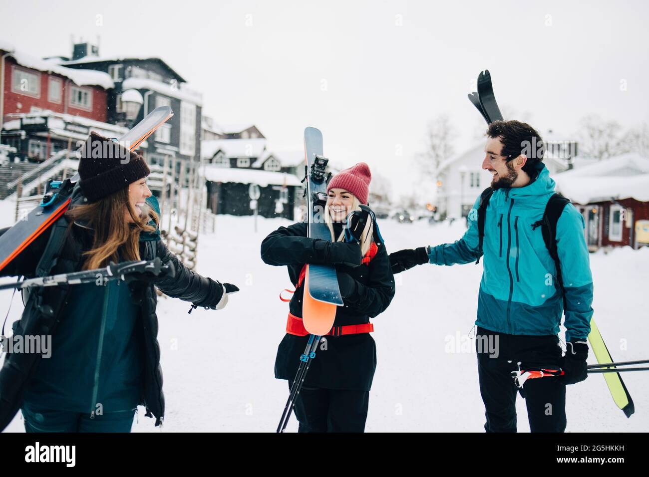 Cheerful male and female friends carrying skis during winter Stock Photo