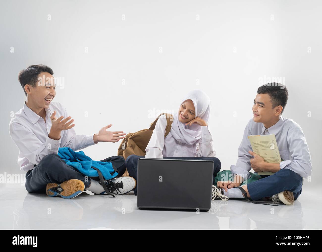 three teenagers in junior high school uniforms sitting on the floor ...