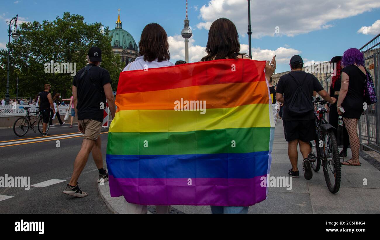 Berlin, Germany - June 26, 2021 - Two women share a rainbow flag on Christopher Street Day (CSD), in the background the Berlin TV tower and the Berlin Stock Photo