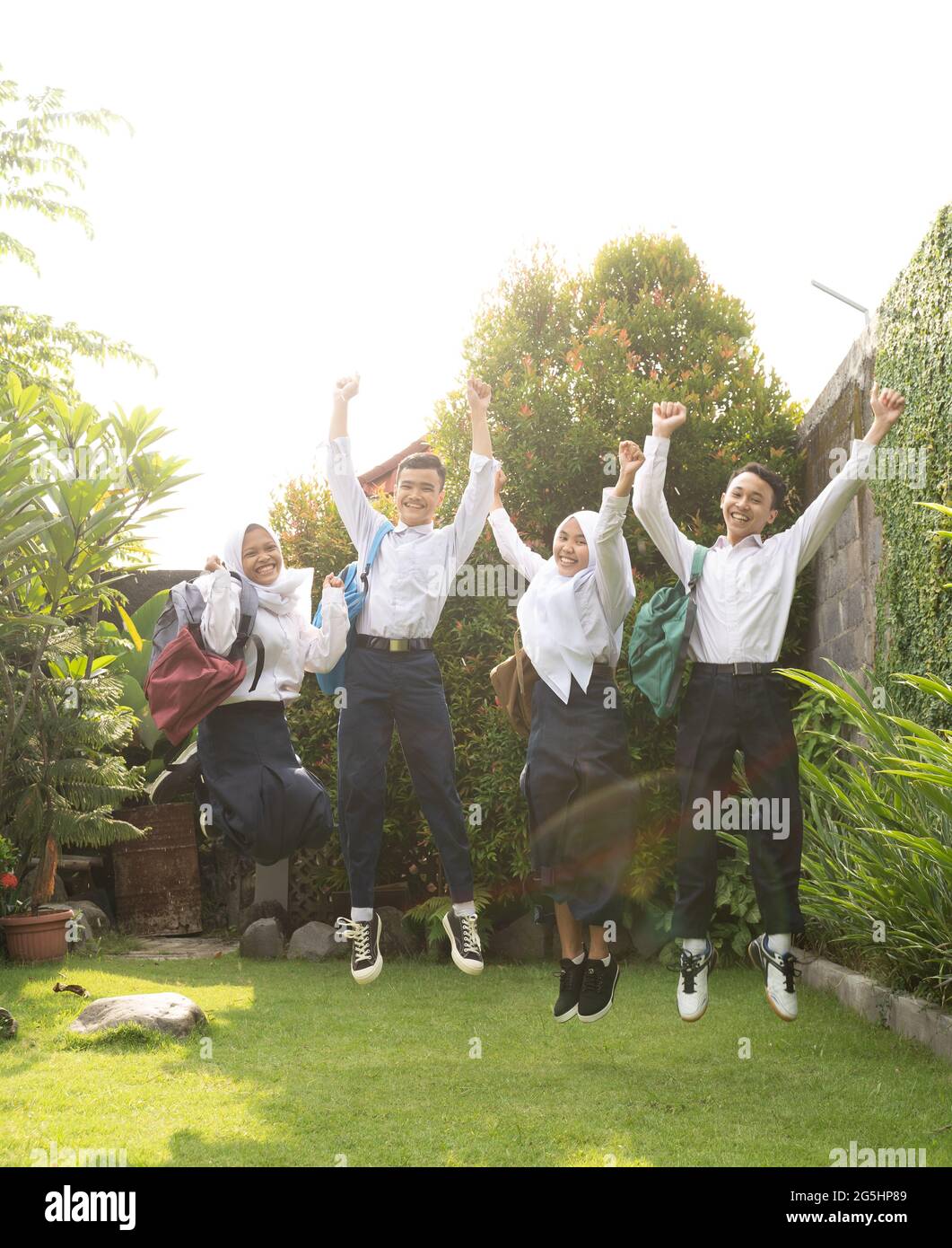 four teenagers hopping cheerfully in junior high school uniforms at the