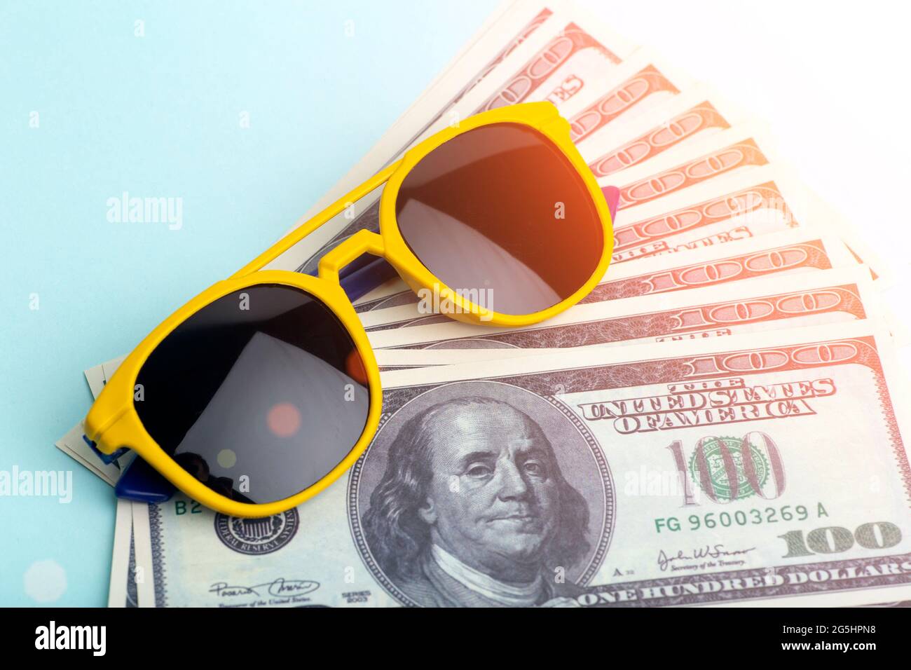 Travel money concept. Sunglasses and USA dollars on a blue background. Budget and cost of travel, summer vacations and vacations. . High quality photo Stock Photo