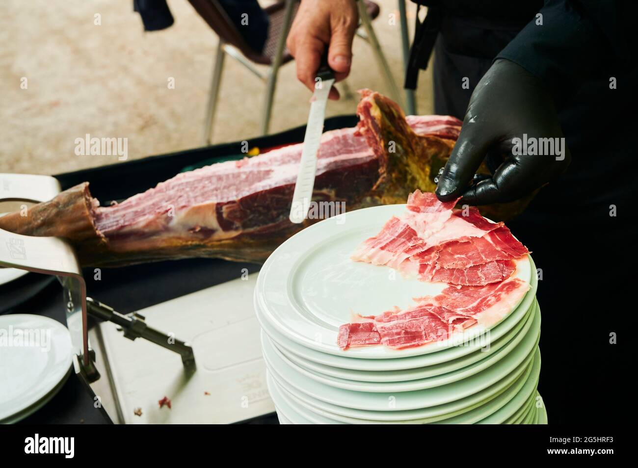 Hands of Master cutter cutting Iberian ham, Spain Stock Photo