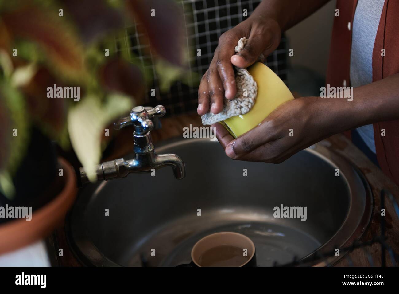 African man washing some dishes in his kitchen sink Stock Photo