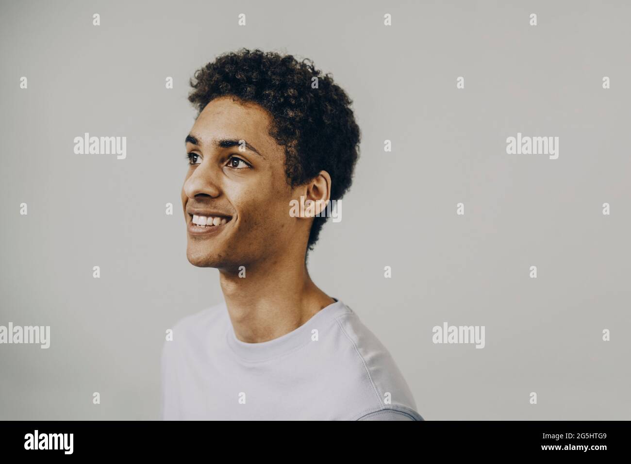 Smiling young man with curly hair against white background Stock Photo