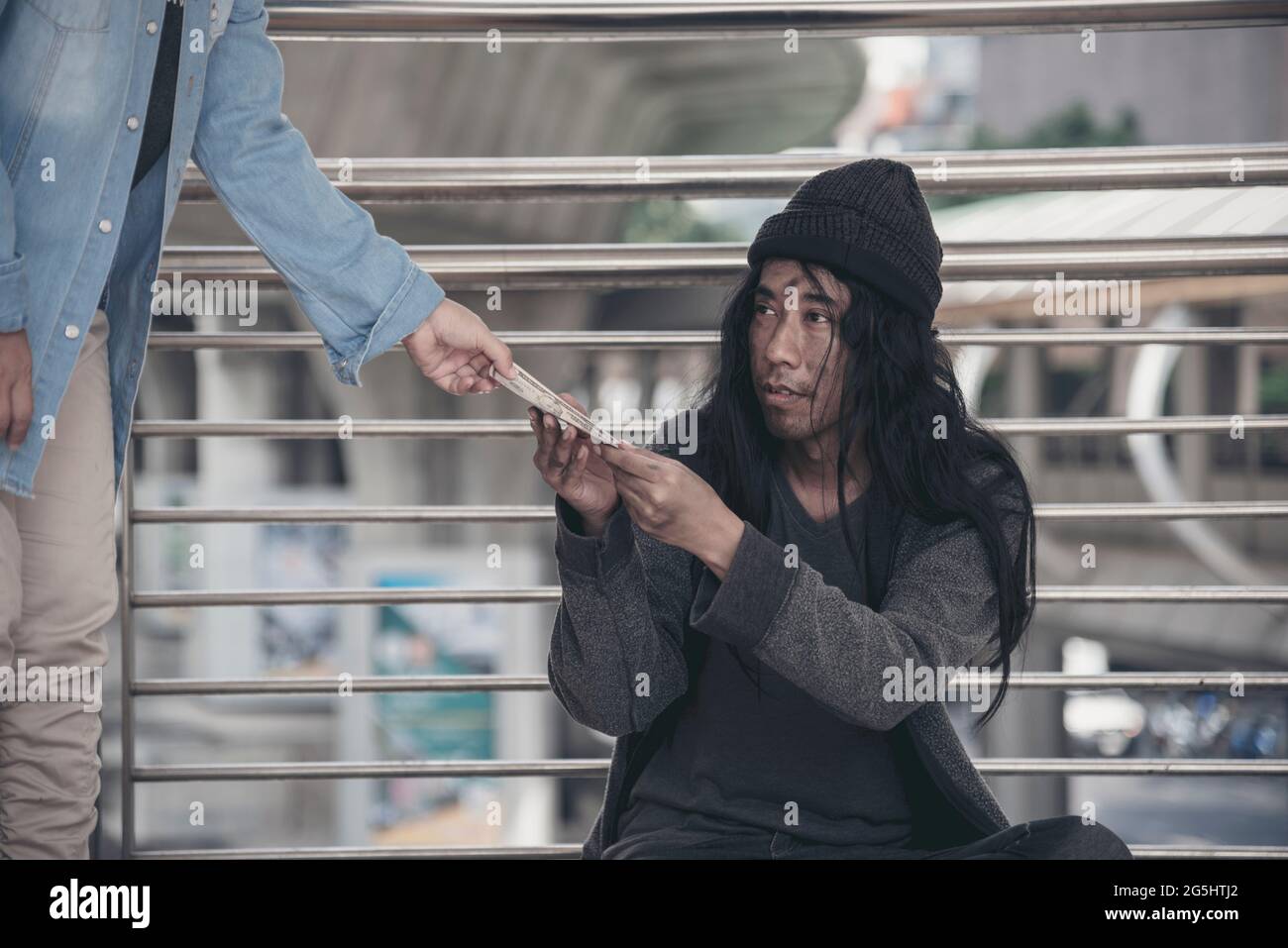 Homeless beggar man begging for money, food and help on street. Poverty despair poor man hungry and loneliness need help from man kind. woman give mon Stock Photo