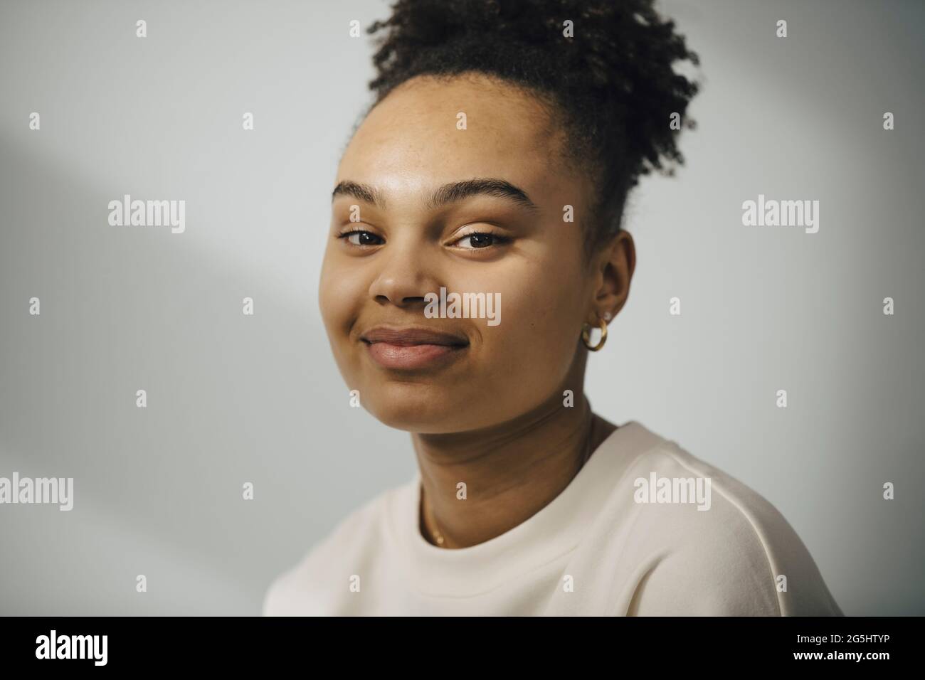 Portrait of smiling young woman against white wall Stock Photo - Alamy