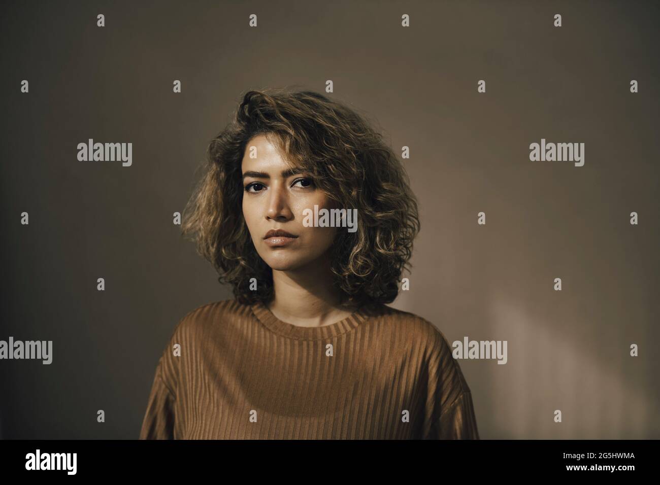 Serious woman curly hair beige hi-res stock photography and images - Alamy