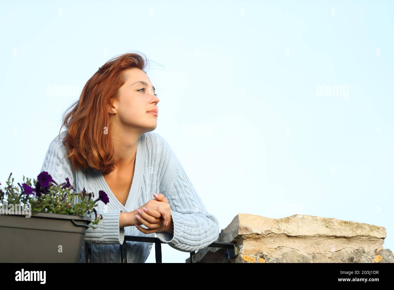 Relaxed woman looking away from a balcony at home Stock Photo