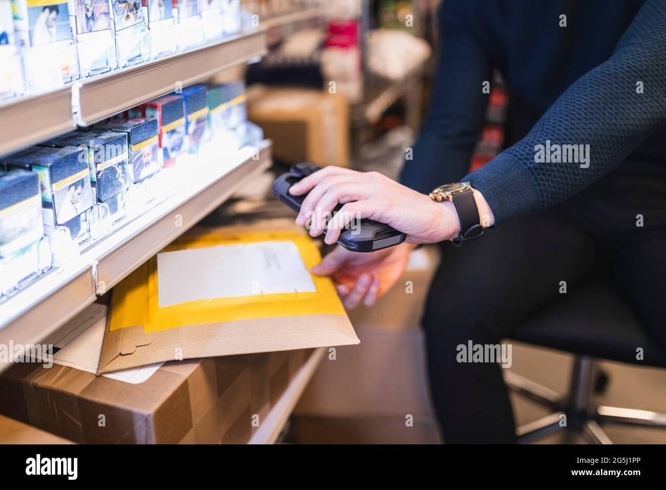 Male entrepreneur using bar code reader while analyzing package in store Stock Photo