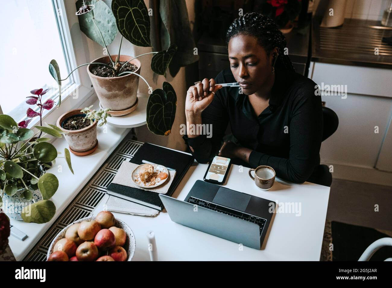Young female entrepreneur sitting with laptop while working from home Stock Photo