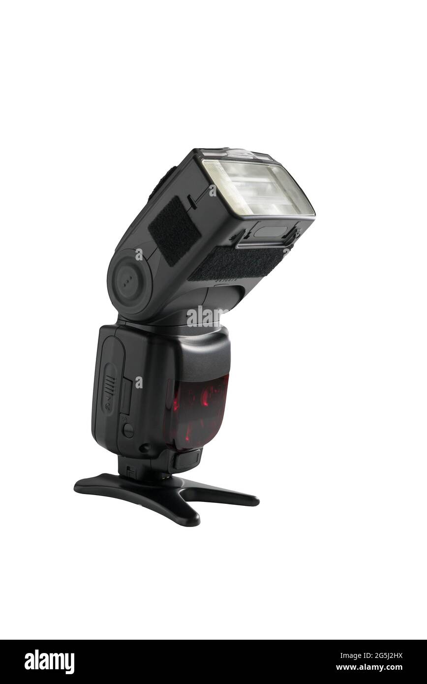 A professional, expensive external remote photography digital travel flash standing on a table tripod, cut out on white background with copyspace. Stock Photo