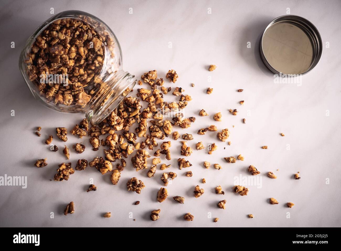 Top view of fresh homemade healthy granola in a glass jar on a breakfast white marble table. Stock Photo