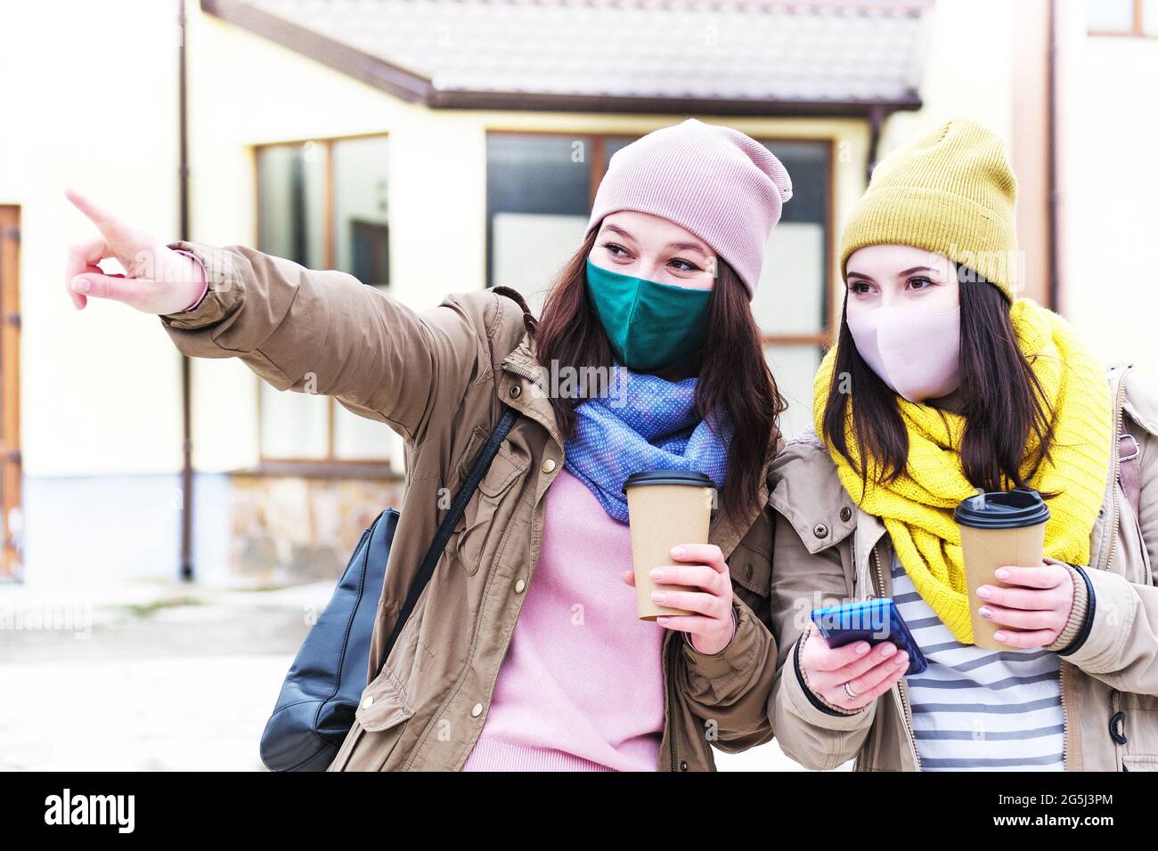 Two young girls travel in the city during the covid epidemic - Girlfriends seek direction while traveling - Concept of a new normal girl with face mas Stock Photo