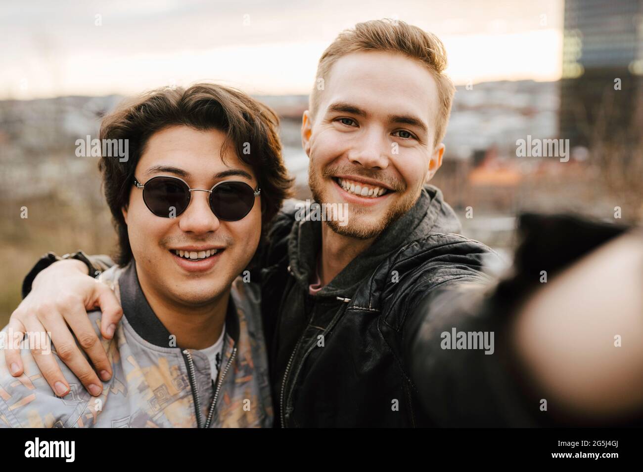 Young male friends smiling while taking selfie Stock Photo
