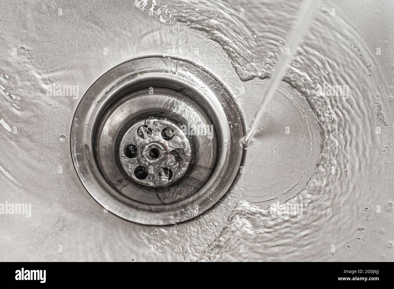 Water flows into the stainless steel kitchen sink drain Stock Photo Alamy