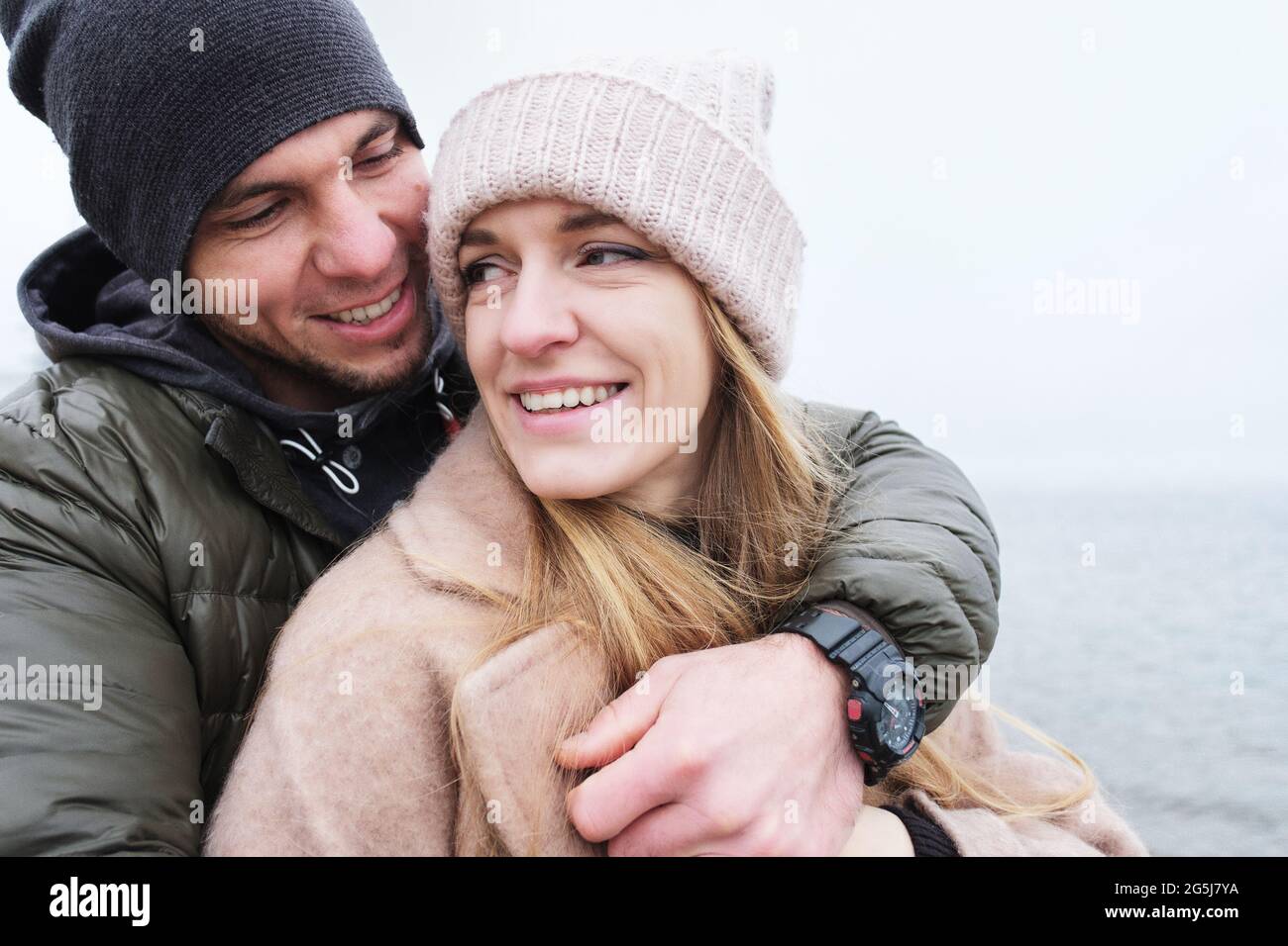 Happy husband and wife are smiling and husband hugs wife tenderly - Couple of young people having fun outdoors - Man and woman together as good friend Stock Photo