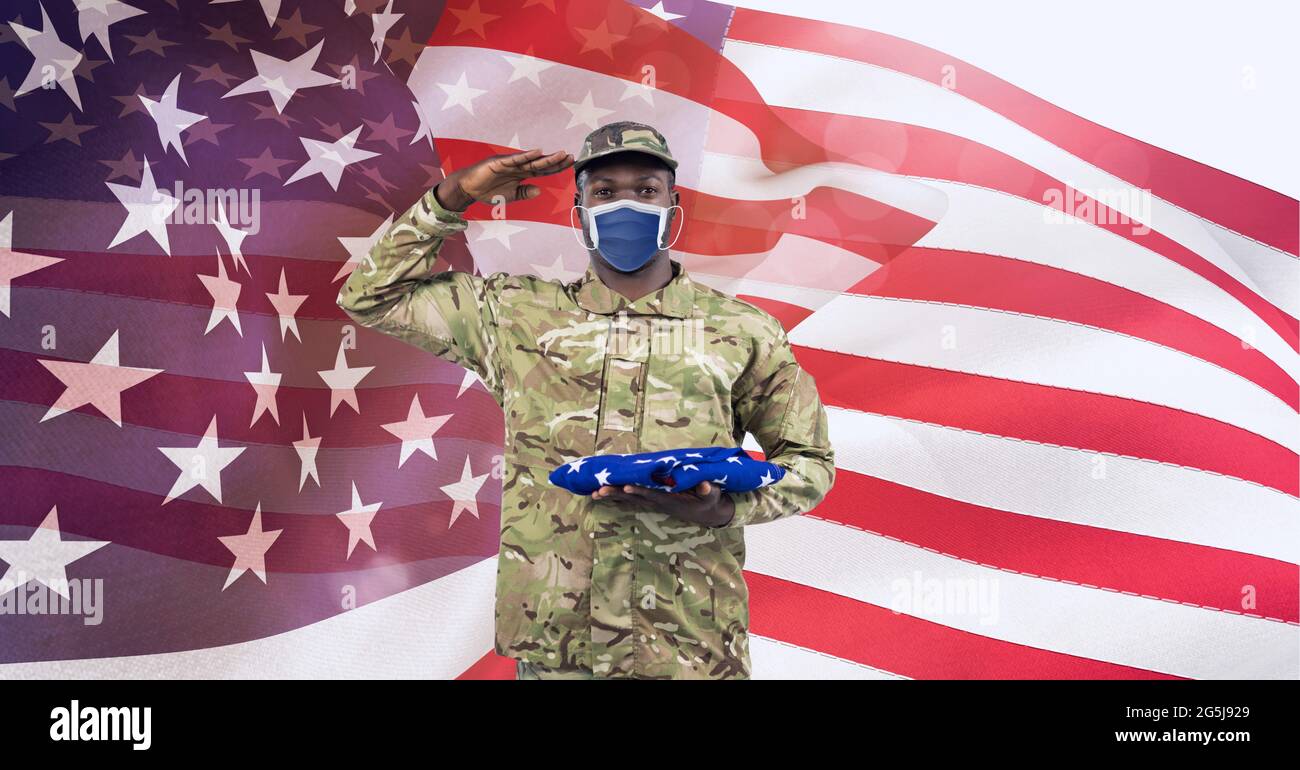 Composition of saluting male soldier wearing face mask holding folded ...