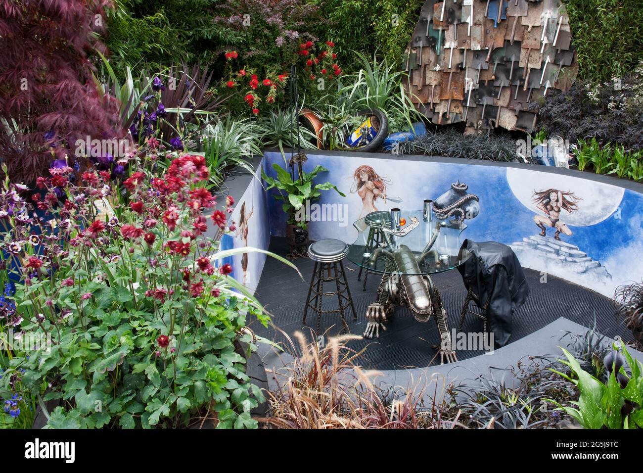 The Ace of Spades' sunken garden with painted wall, spade sculpture, old bike parts, tyres, dark