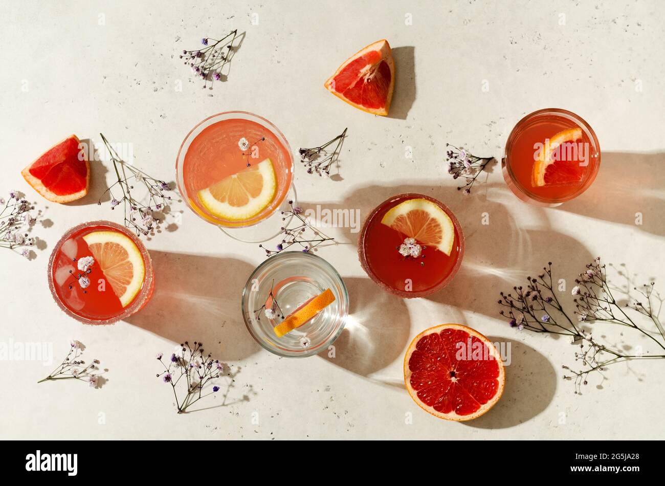Set of glasses and glasses with different cocktails with hard shadows on a light background and flat layout Stock Photo