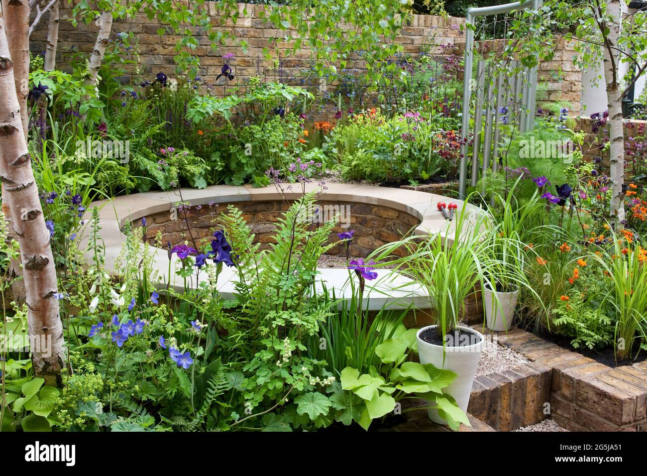 Small courtyard garden, aluminium wind chime, seating area, reclaimed brick walls Stock Photo