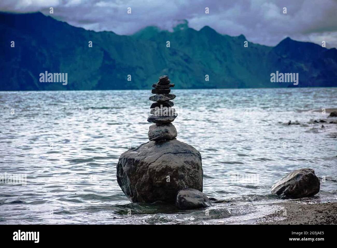 Big rock with many rocks on top of each other it on the sandy beach ...
