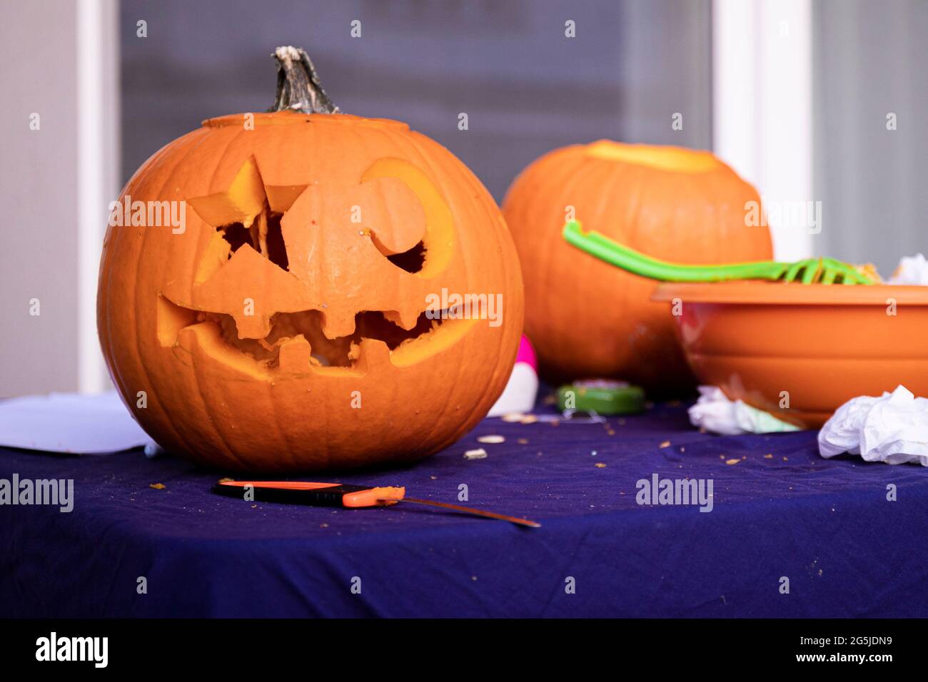 carving a pumpkin on Halloween day, on a blue tablecloth with no people, to make a jack'o Lantern with star and moon eyes. Stock Photo