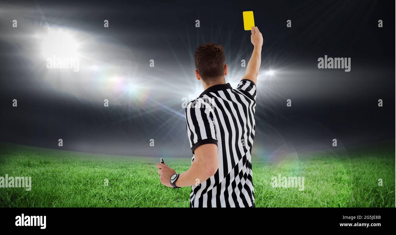 Composition of male referee holding yellow card at football stadium Stock Photo
