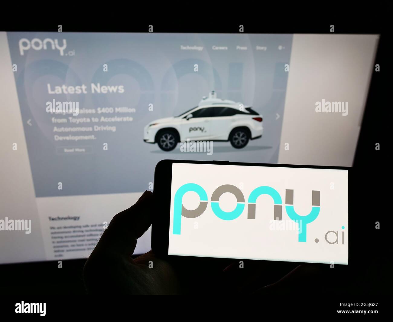 Person holding cellphone with logo of autonomous vehicle company Pony.AI Inc. on screen in front of business webpage. Focus on phone display. Stock Photo