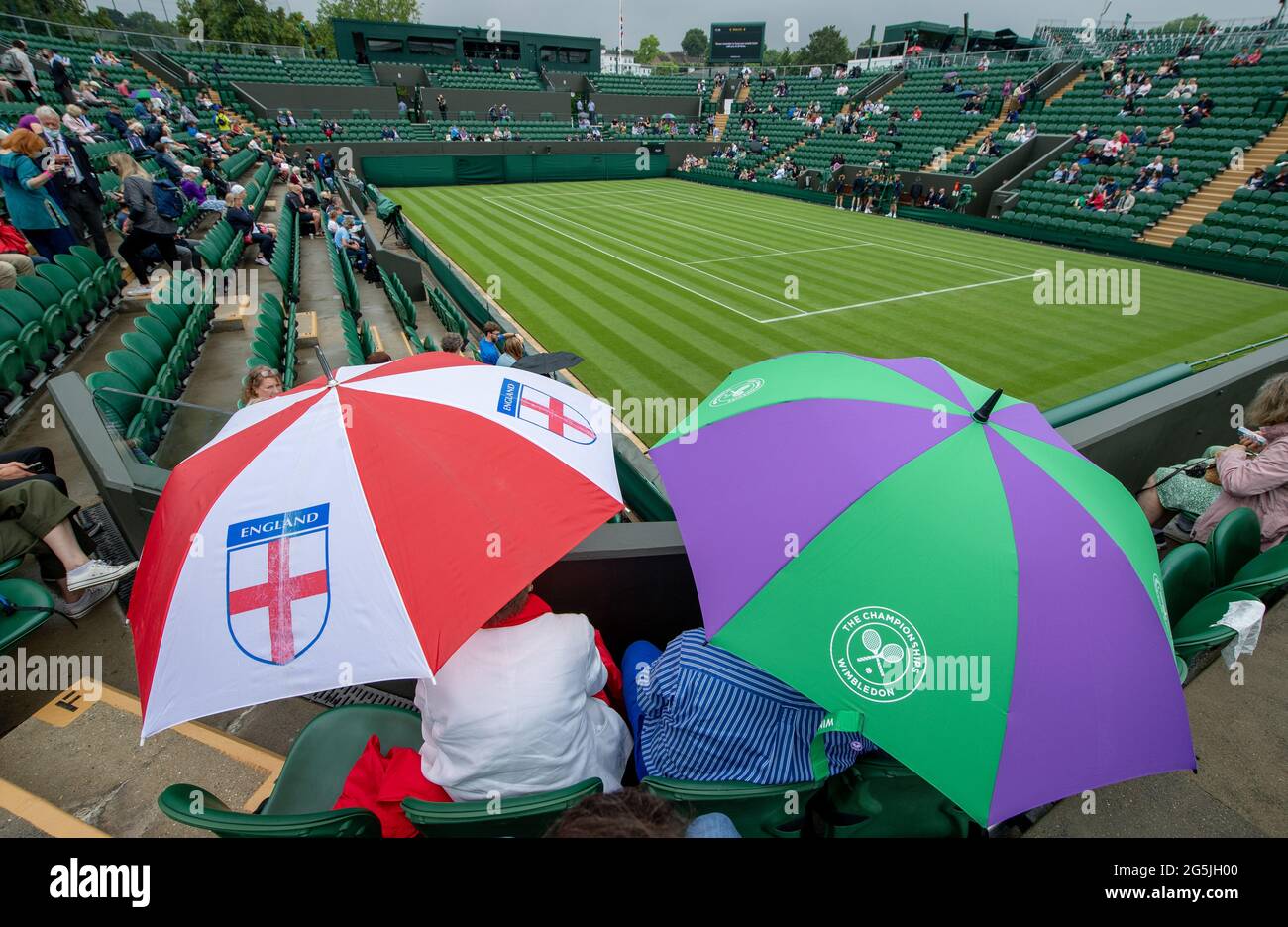 Ticket holders shelter under England and Wimbledon umbrellas on No.2