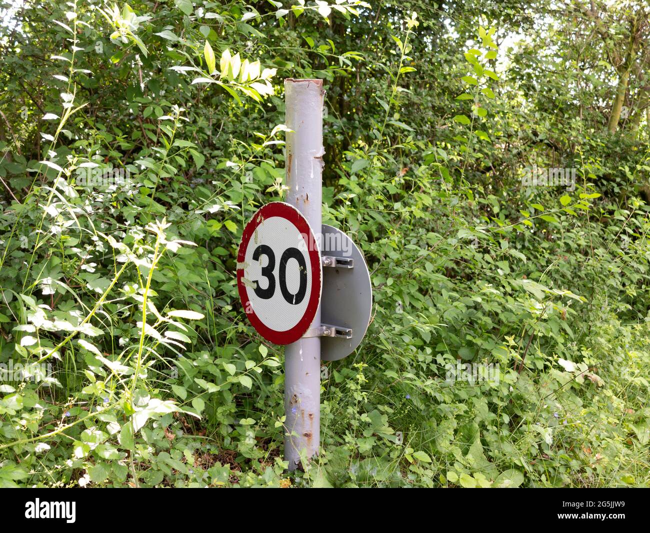 Short post mounted 30 miles per hour limit road sign in a rural setting Stock Photo
