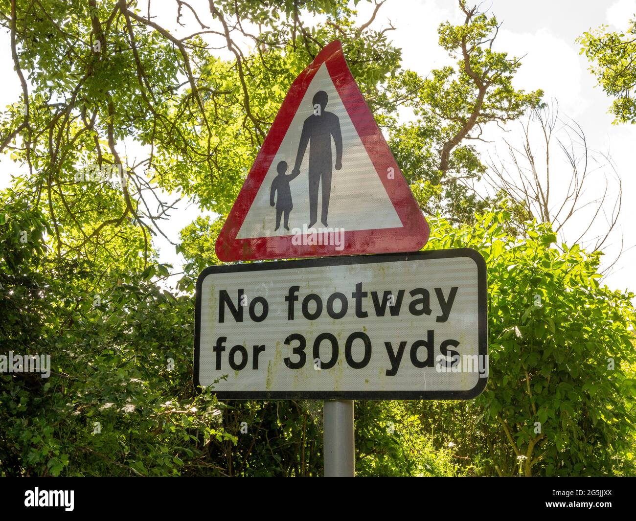 A roadside sign indicating that there is 'No footway for 300 yds' using words and an adult figure and child symbol in a warning red triangle Stock Photo