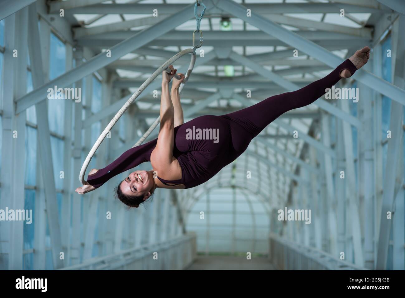 An air gymnast makes a Russian splits on an air hoop suspended on a metal truss. circus actress on the airy ring. Stock Photo