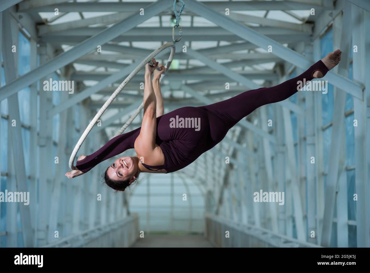 An air gymnast makes a Russian splits on an air hoop suspended on a metal truss. circus actress on the airy ring. Stock Photo