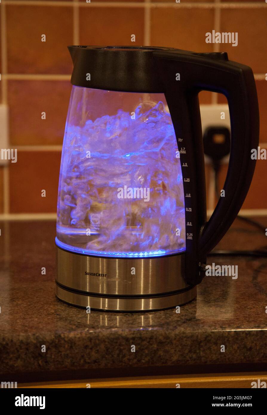 A see-through kettle boiling water, illuminated by a blue light inside Stock Photo