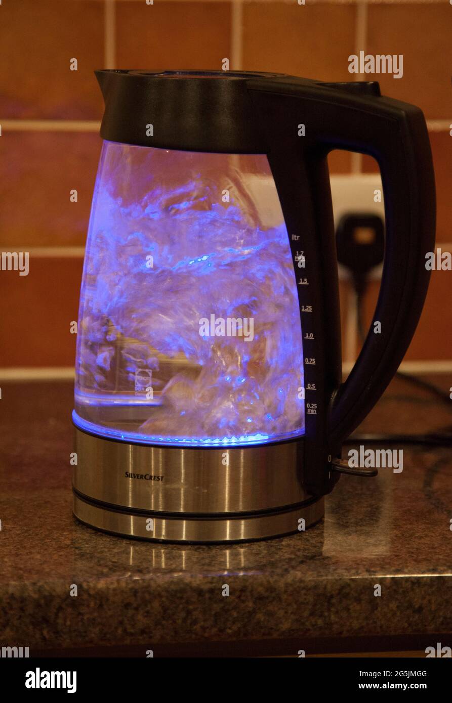 A see-through kettle boiling water, illuminated by a blue light inside Stock Photo