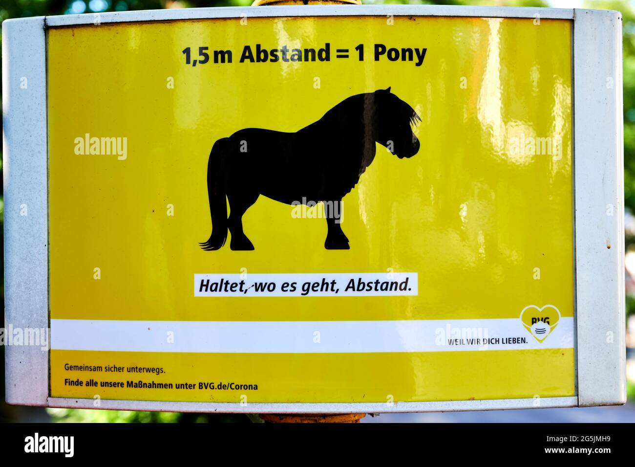 Berlin; Germany - June 27; 2021: Humorous notice at a bus stop of the Berliner Verkehrsbetriebe (BVG) that, due to the corona pandemic, a distance tha Stock Photo